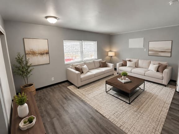 A living room with a white couch, a coffee table, and a plant.